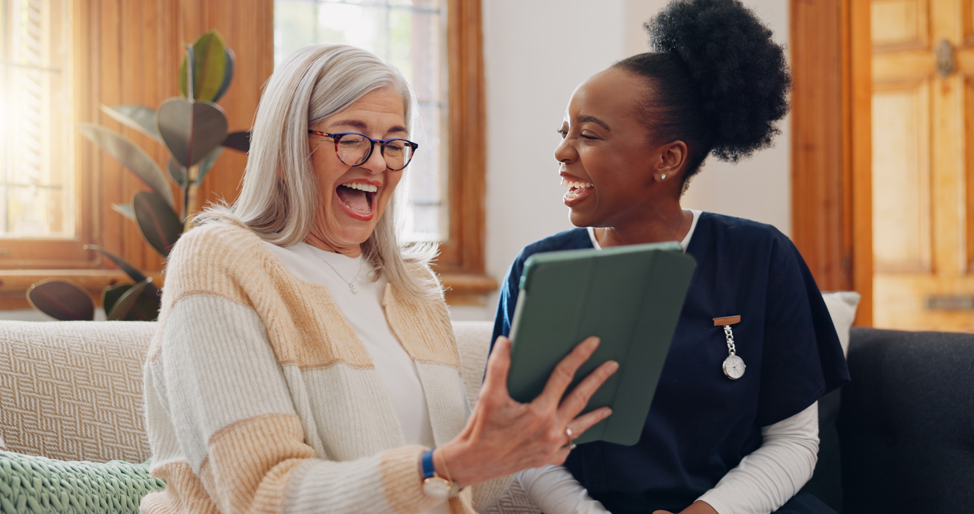 Senior, woman and caregiver with tablet for consulting, medical information and health communication on sofa. Elderly, professional and nurse with touchscreen for online report, advisory and results