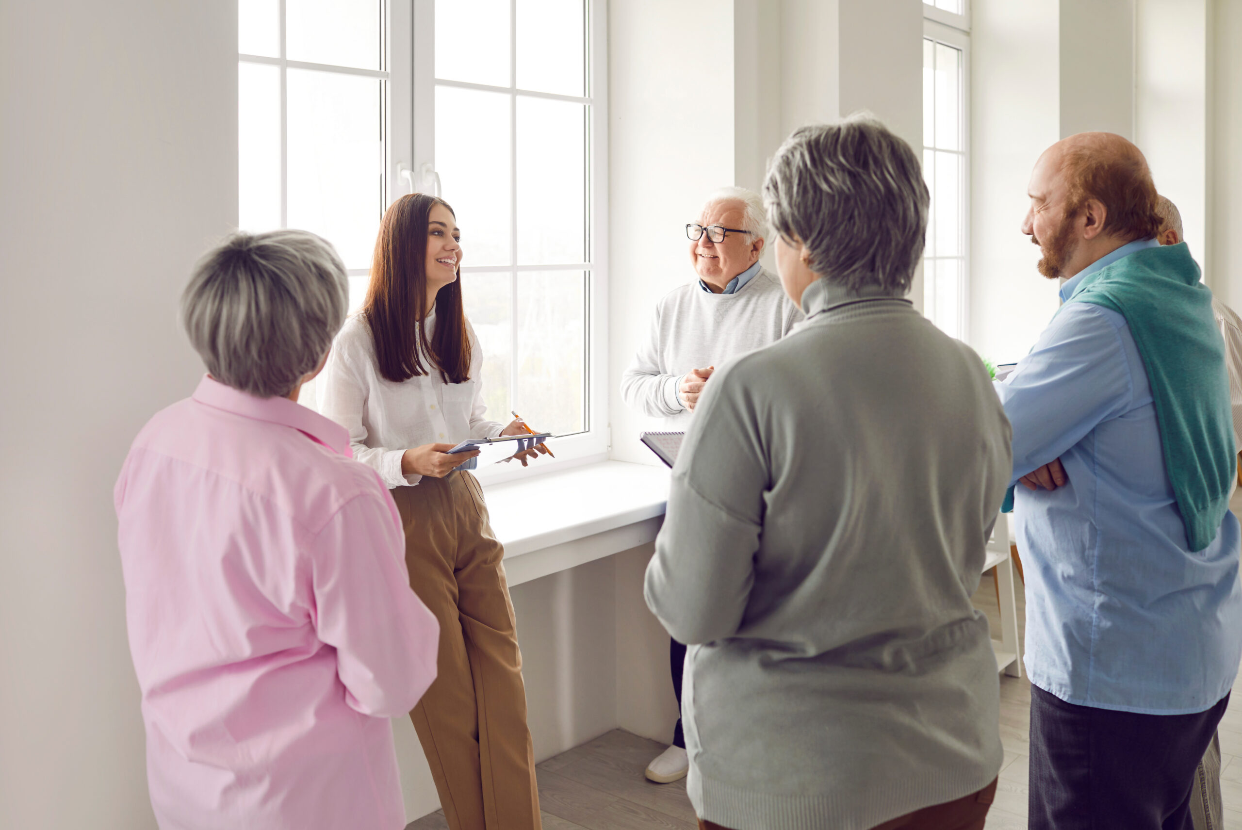 Group of seniors listening psychologist woman speaking on a meeting in nursing home.